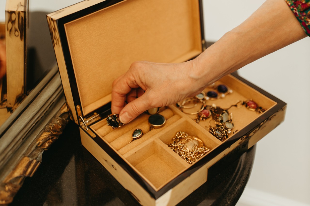 a person’s handing reaching into a jewelry box and selecting a ring