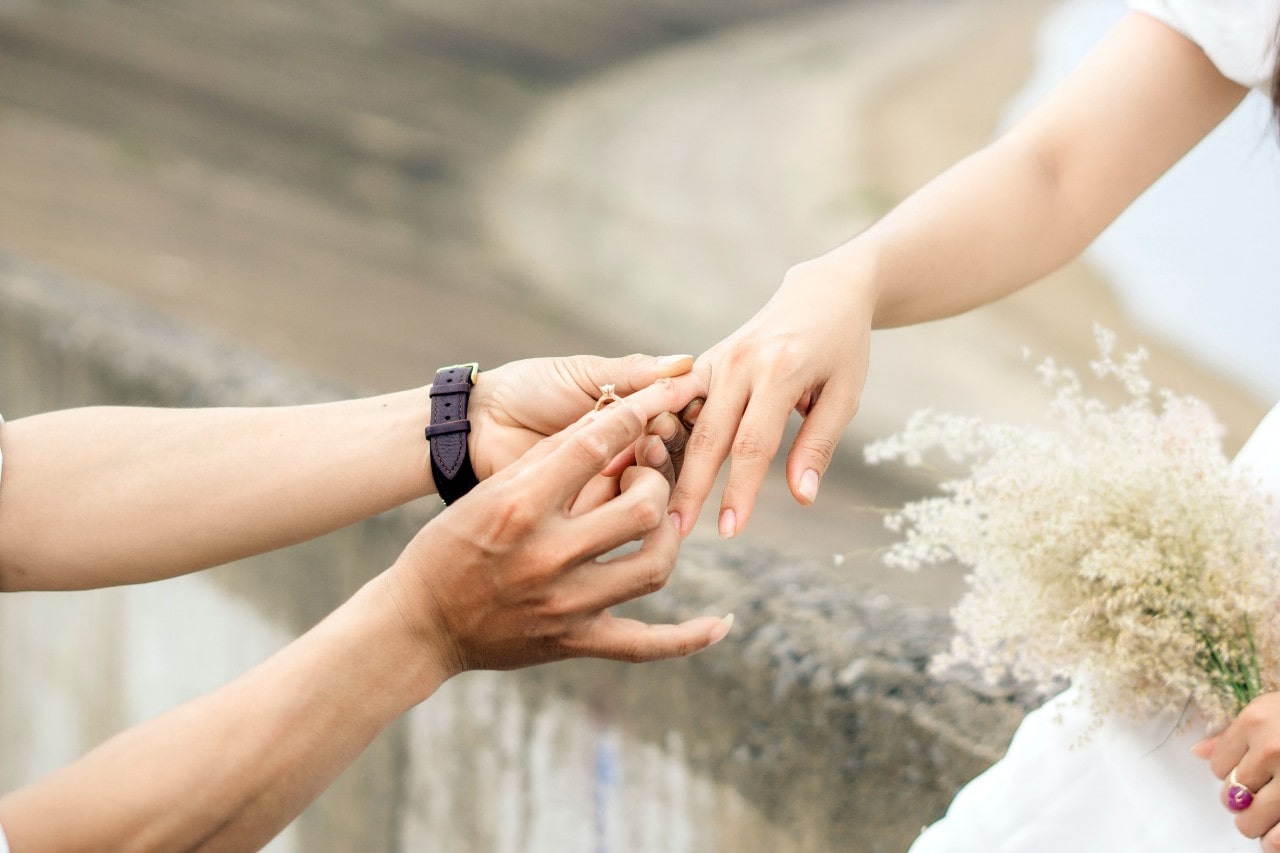 A woman slips an engagement ring on another woman’s finger.