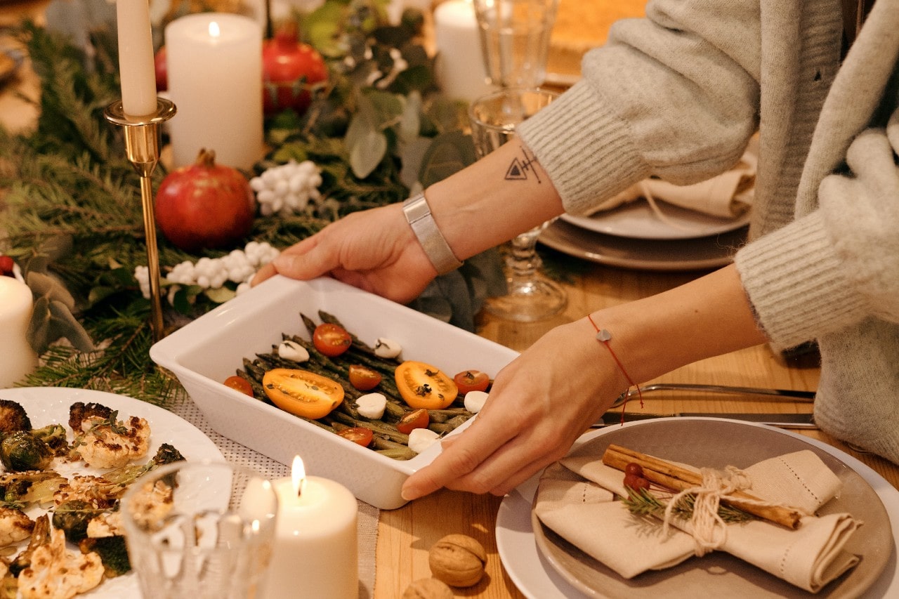a person placing a dish on a table set for Thanksgiving