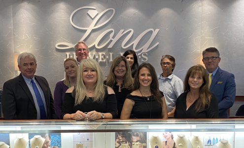 A photograph of the Long Jewelers team behind an elegant necklace display.