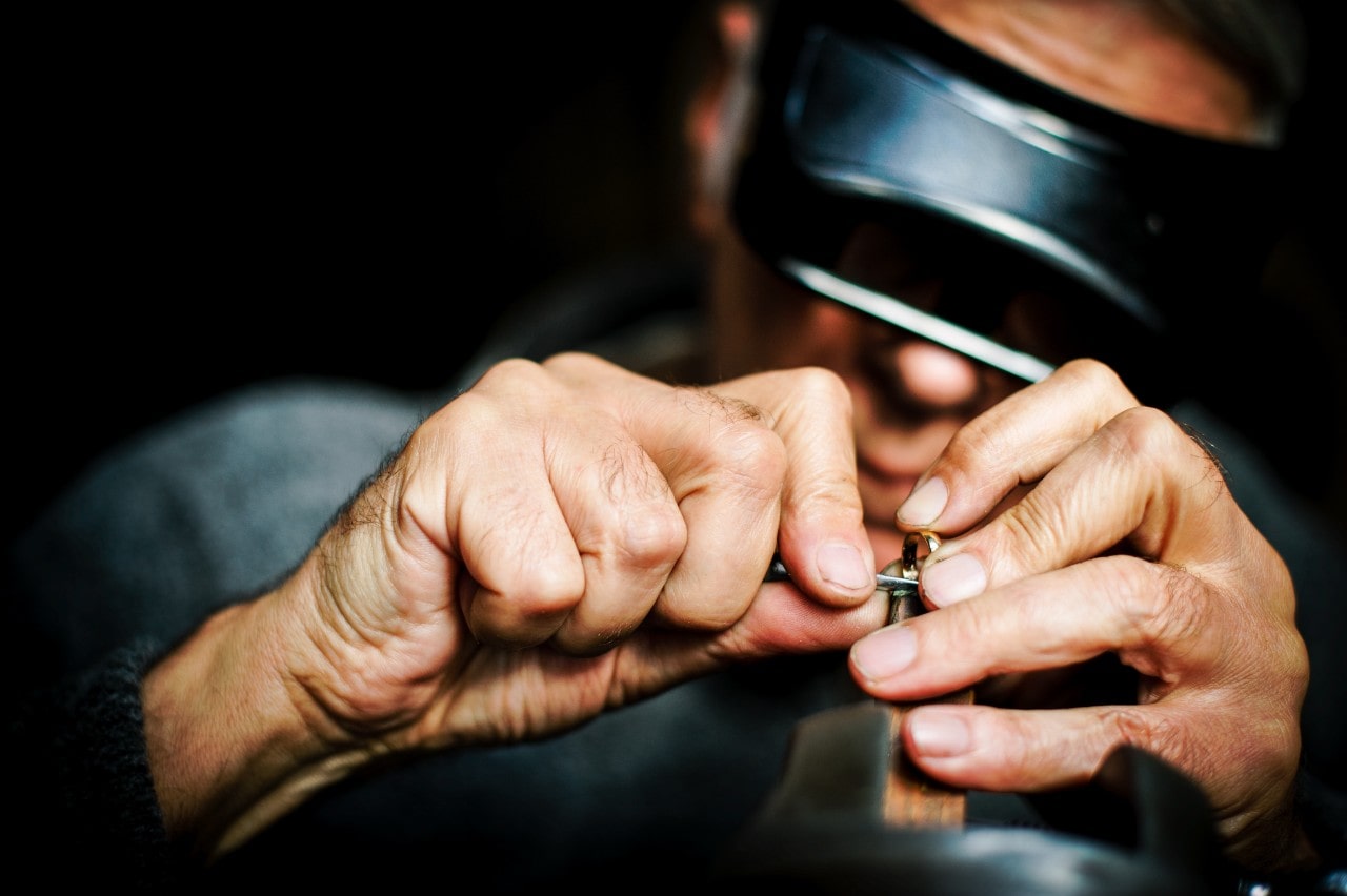 A close-up of a jeweler carefully repairing a ring.