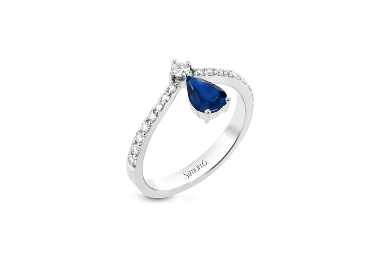 A diamond ring with a diamond studded band and a pear shaped dark blue center stone.