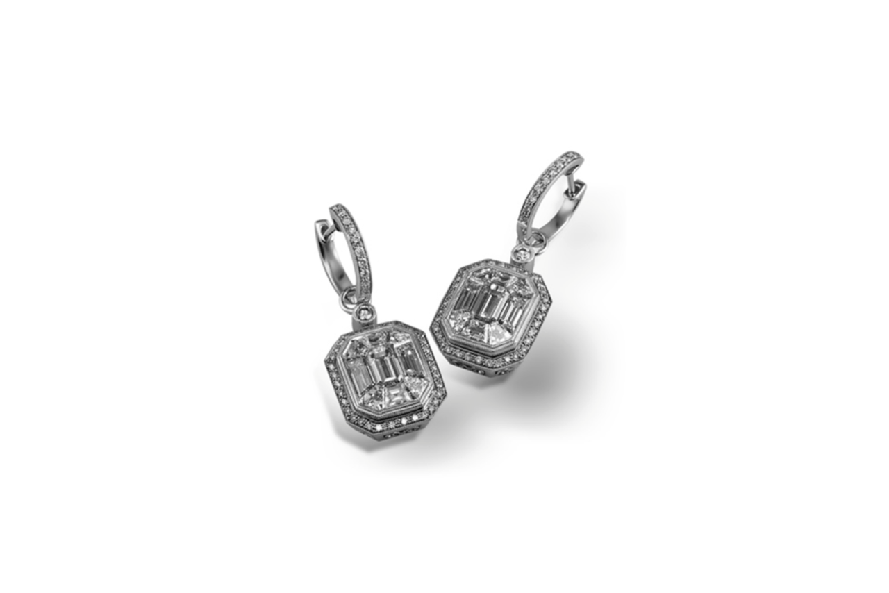 Emerald cut diamond earrings hanging from diamond studded huggies.
