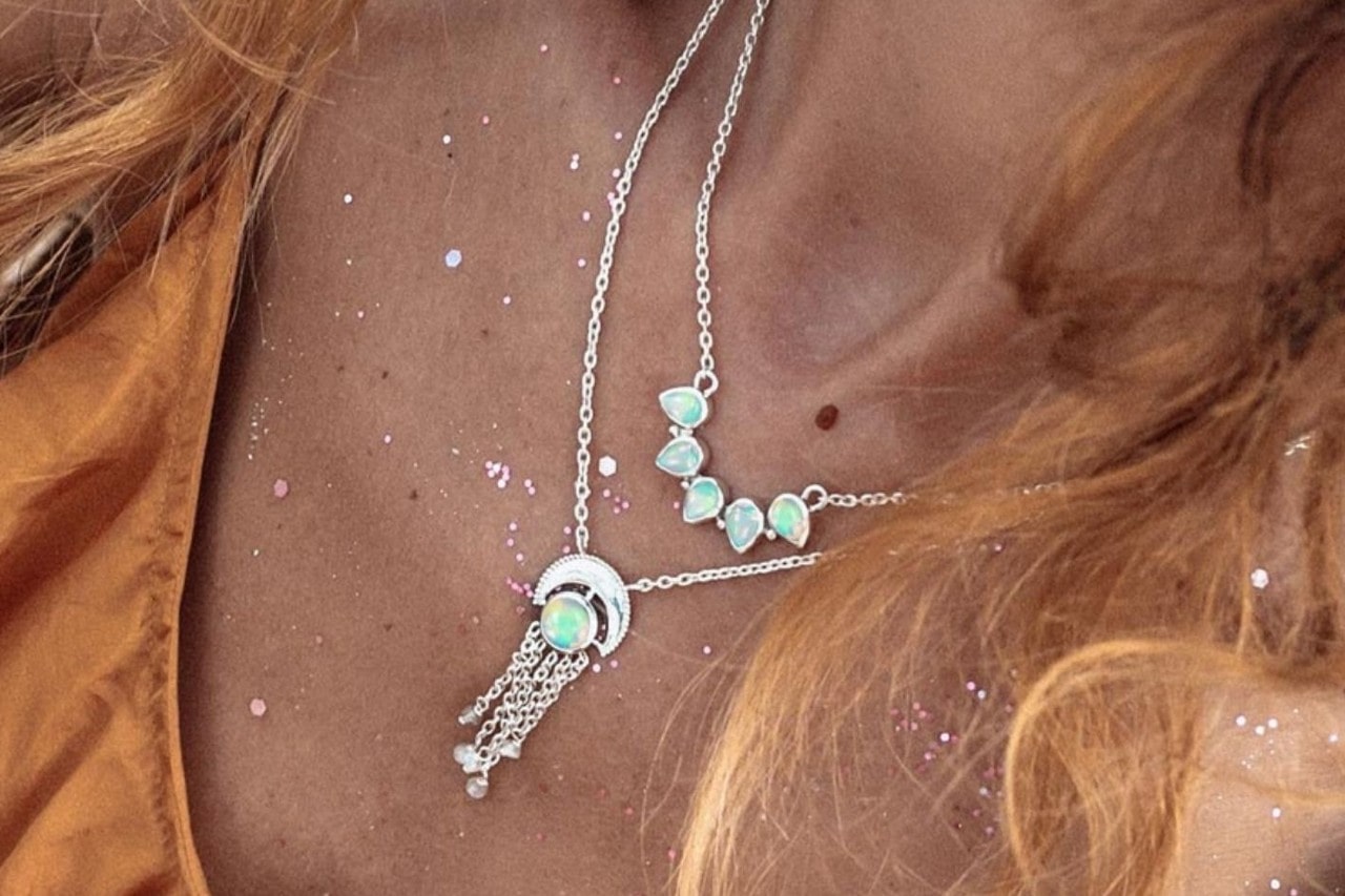 close up image of a woman’s neckline adorned with two opal necklaces
