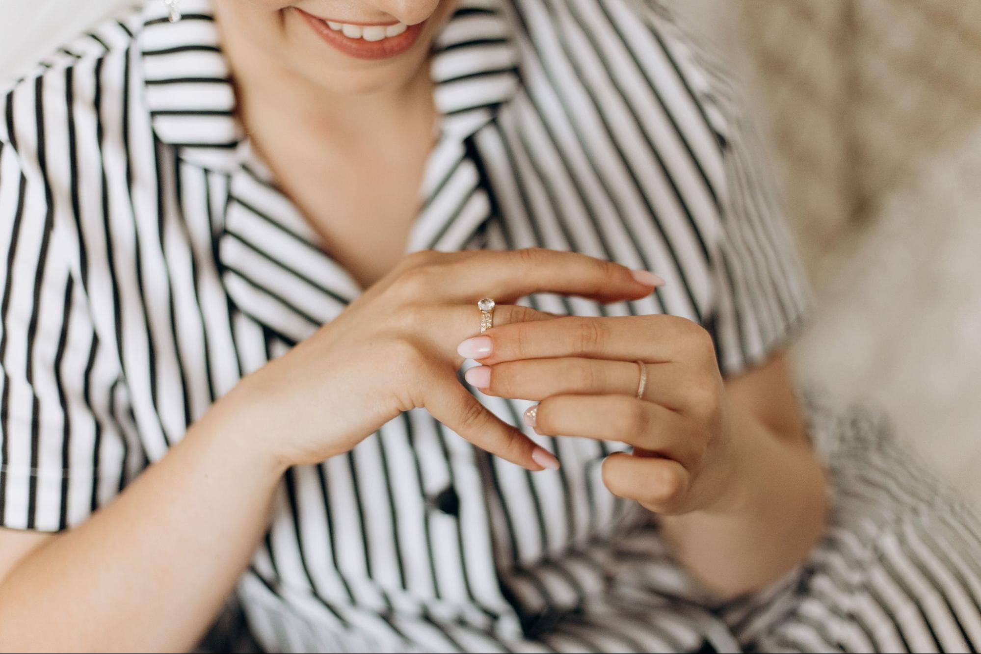 Smiling woman in striped shirt trying on a ring in boutique.