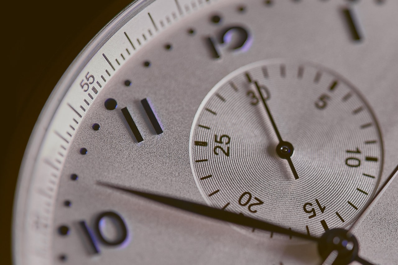 Close-up of a white watch dial with arab numerals.