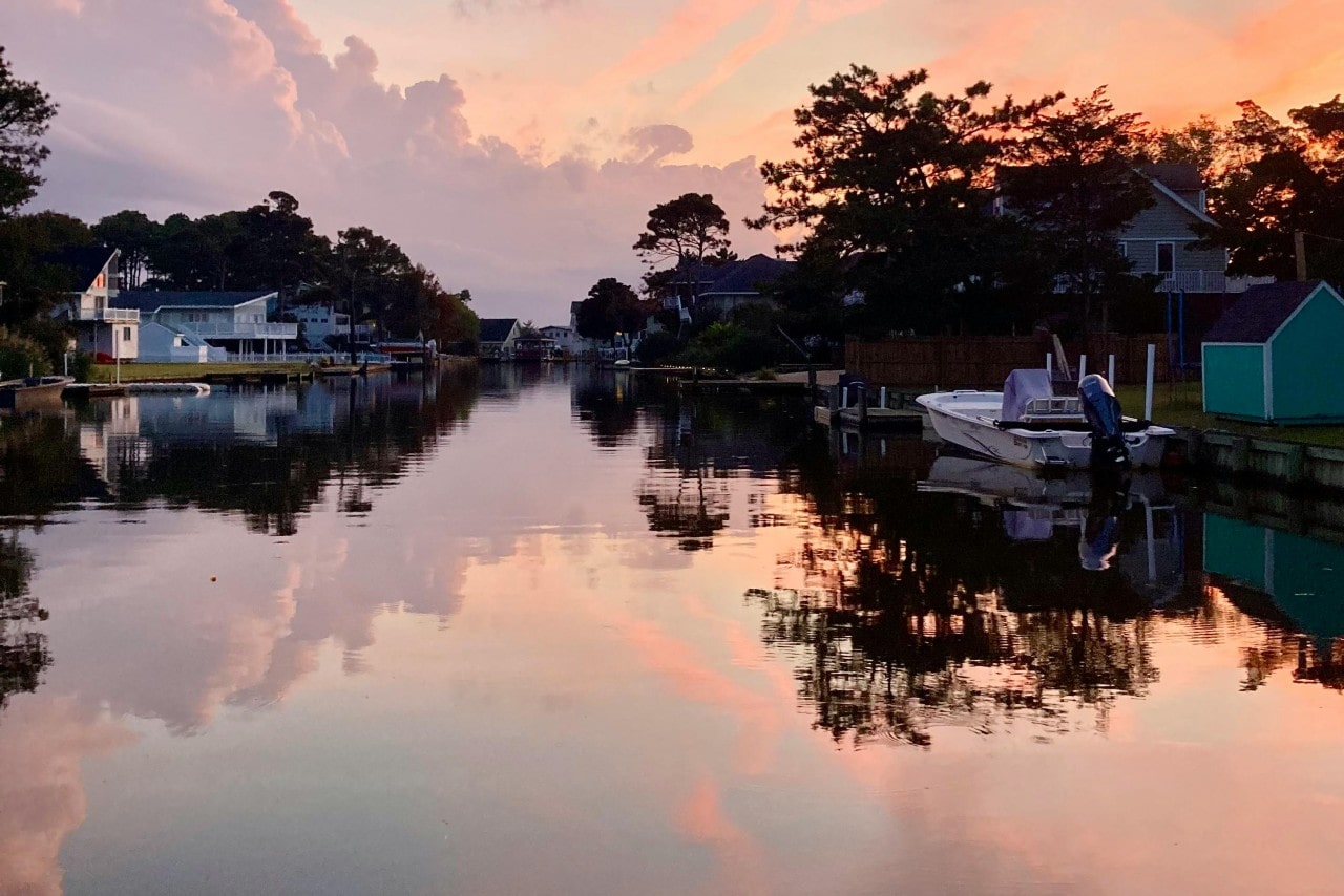 A stunning sunset view of a river in Virginia Beach studded with homes and boats.