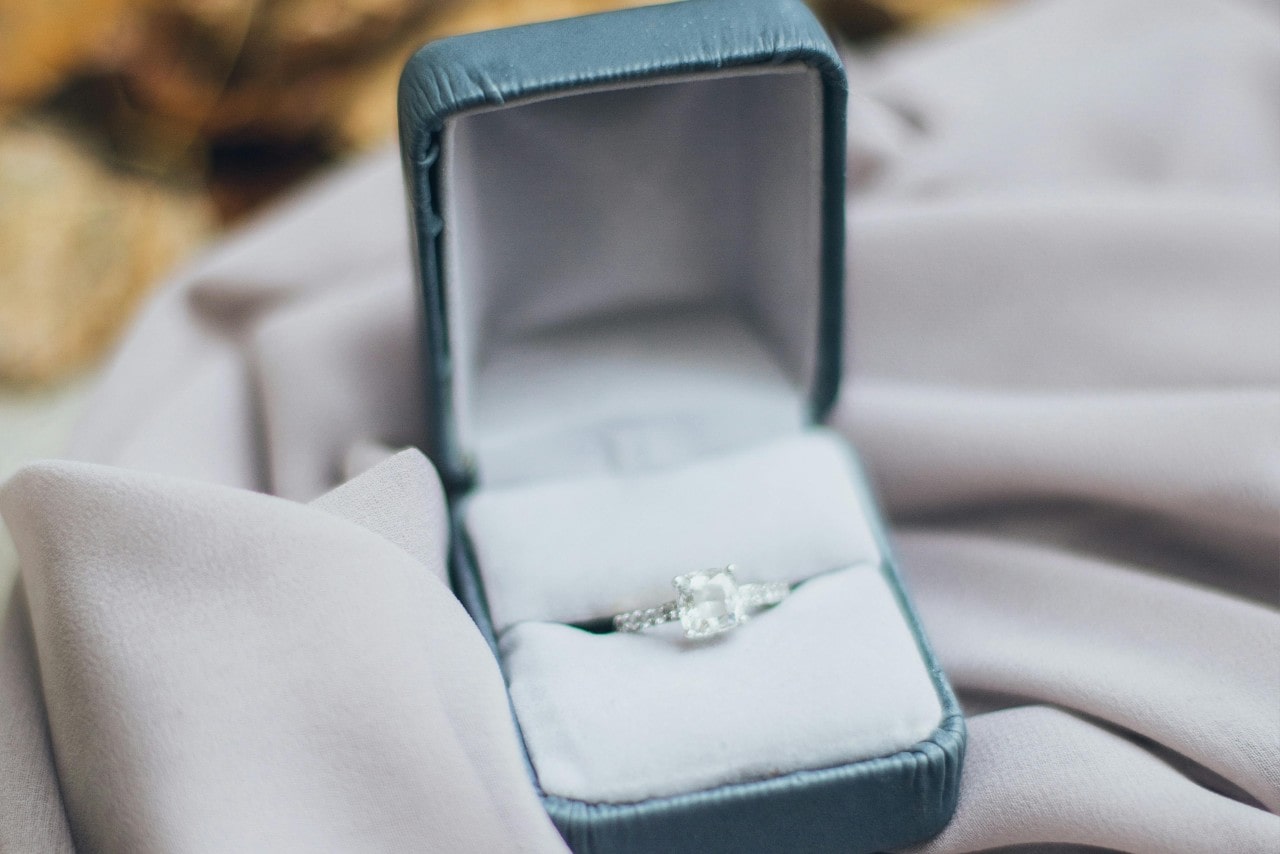 a diamond engagement ring in a blue ring box