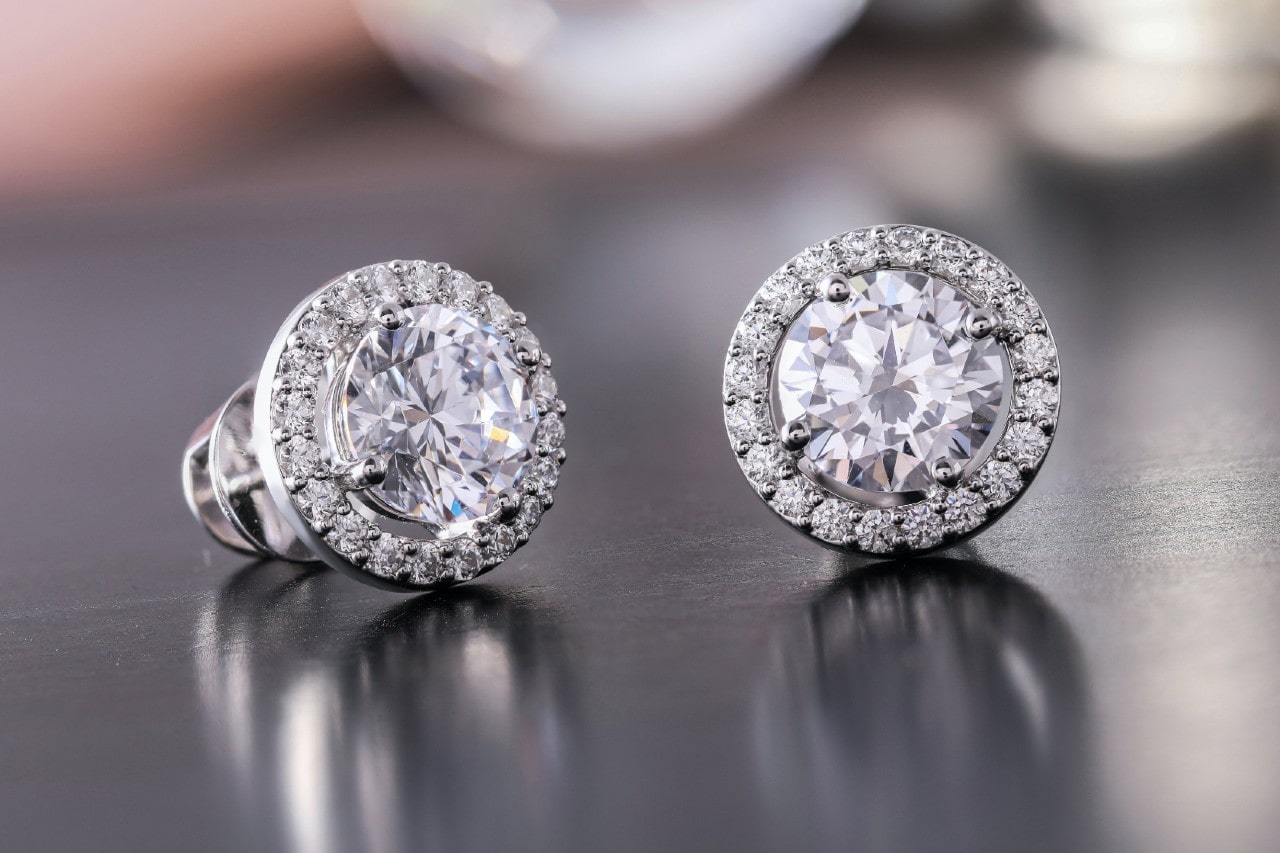 platinum and diamond stud earrings on a wood surface