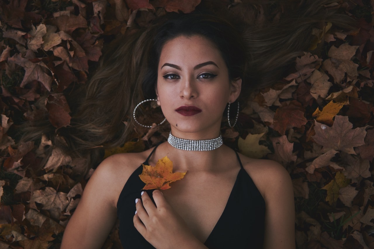 lady lying on autumn leaves and wearing a diamond necklace