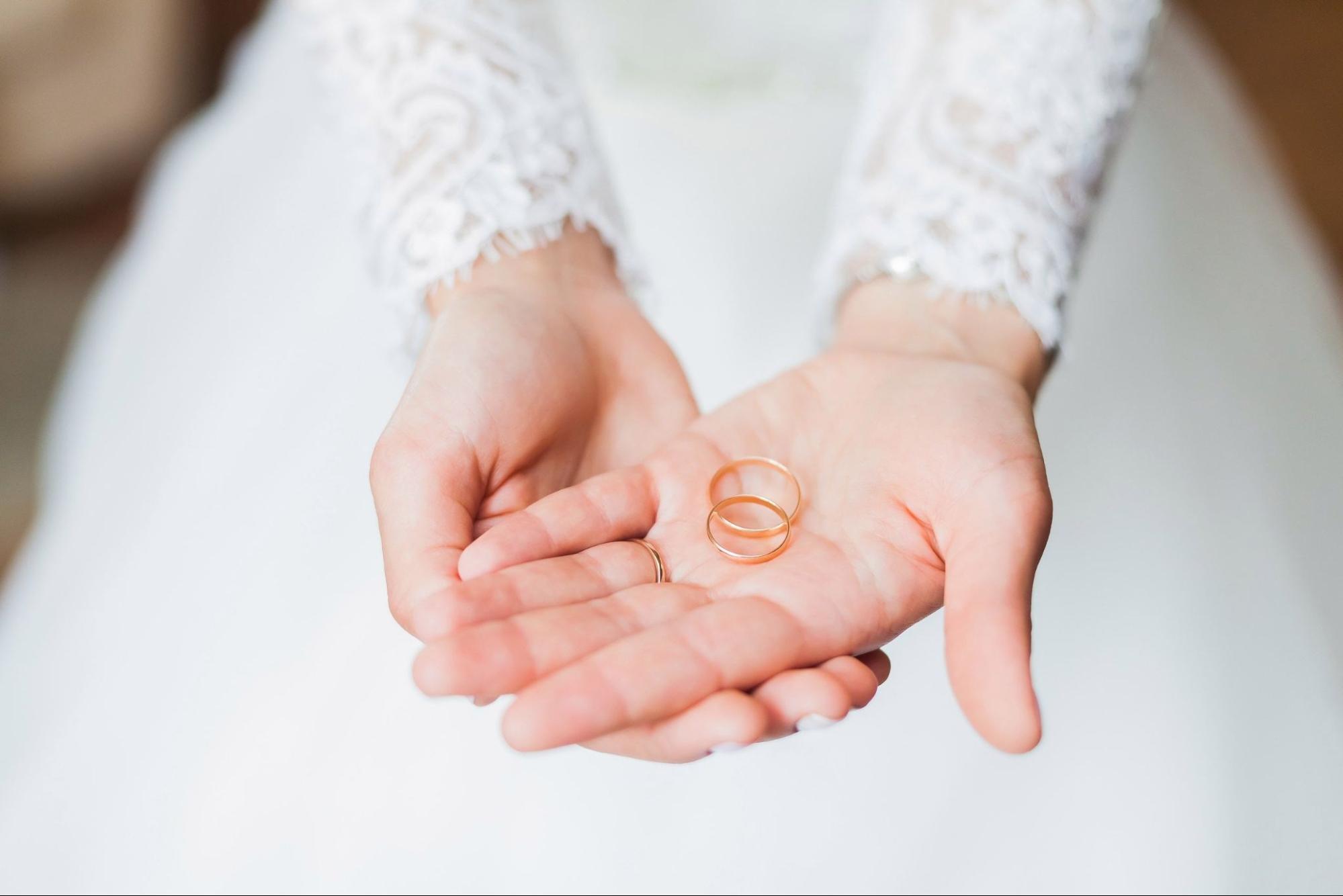 woman holding two wedding bands woman holding two wedding bands