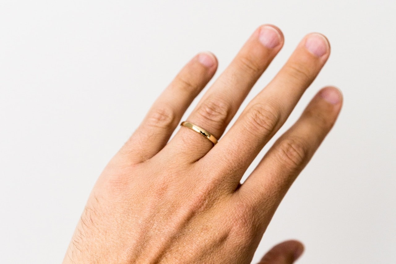 a man’s hand adorned with a simple gold wedding band a man’s hand adorned with a simple gold wedding band