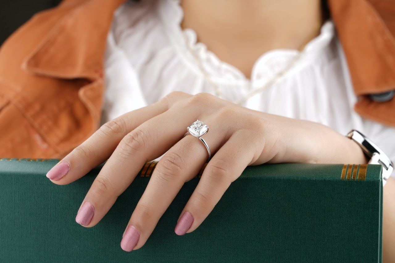 a lady wearing an engagement ring with her hand on a book a lady wearing an engagement ring with her hand on a book