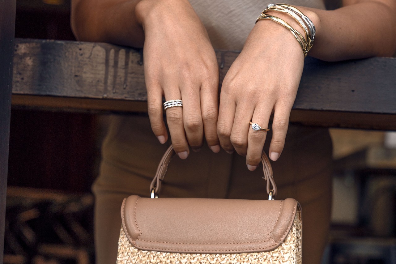 A woman’s arms resting on a post and holding a purse, her hands adorned with TACORI jewelry. A woman’s arms resting on a post and holding a purse, her hands adorned with TACORI jewelry.