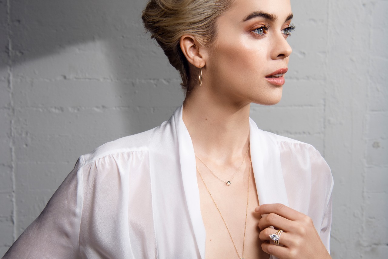 A woman wearing a white top and TACORI jewelry, looking away from the camera. A woman wearing a white top and TACORI jewelry, looking away from the camera.