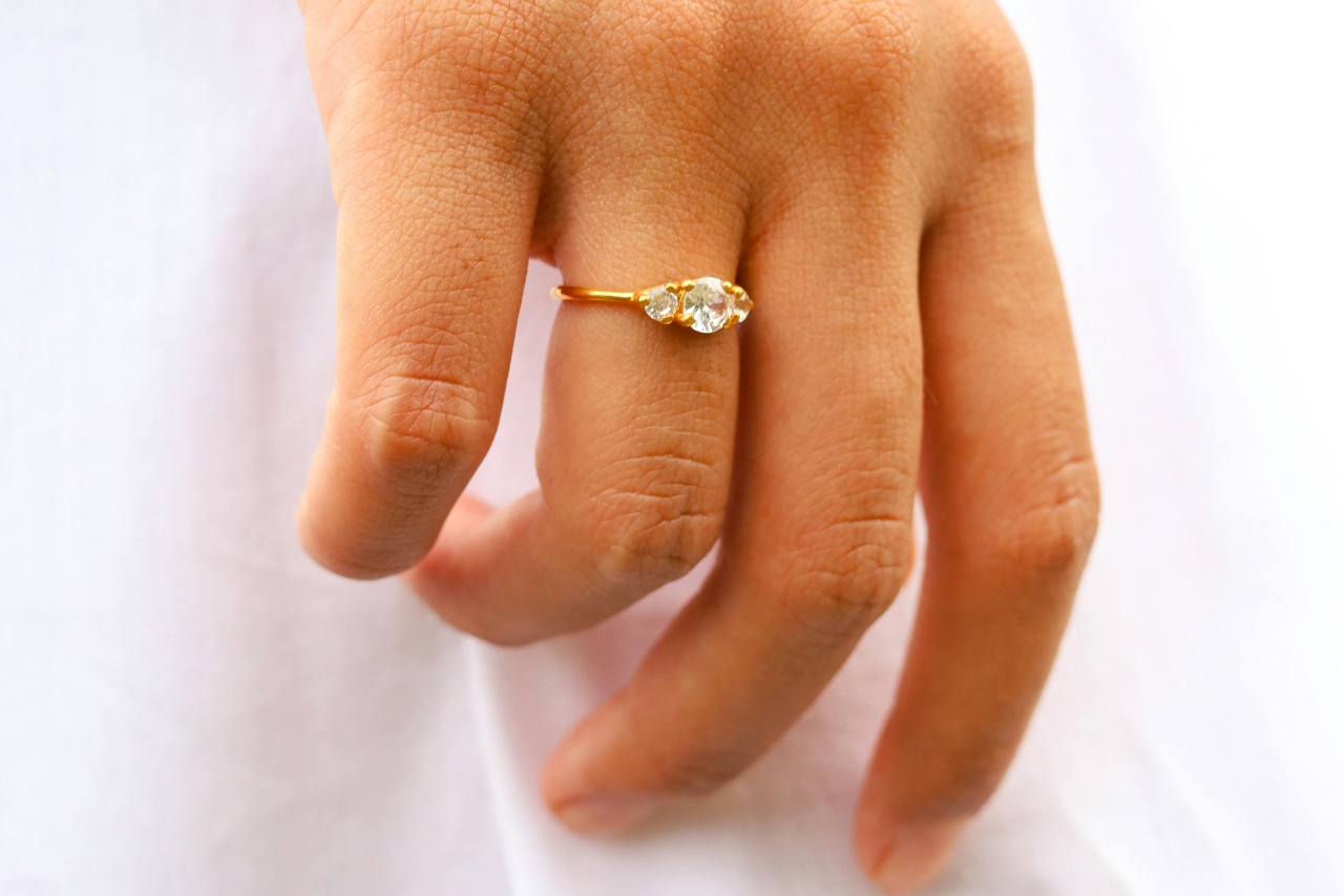 A yellow gold diamond three stone engagement ring on a woman’s hand.