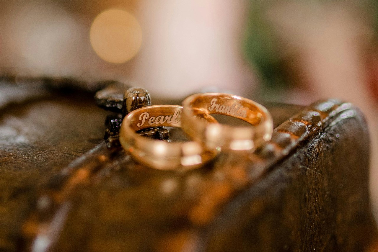 A close-up of two gold wedding bands engraved with the names A close-up of two gold wedding bands engraved with the names