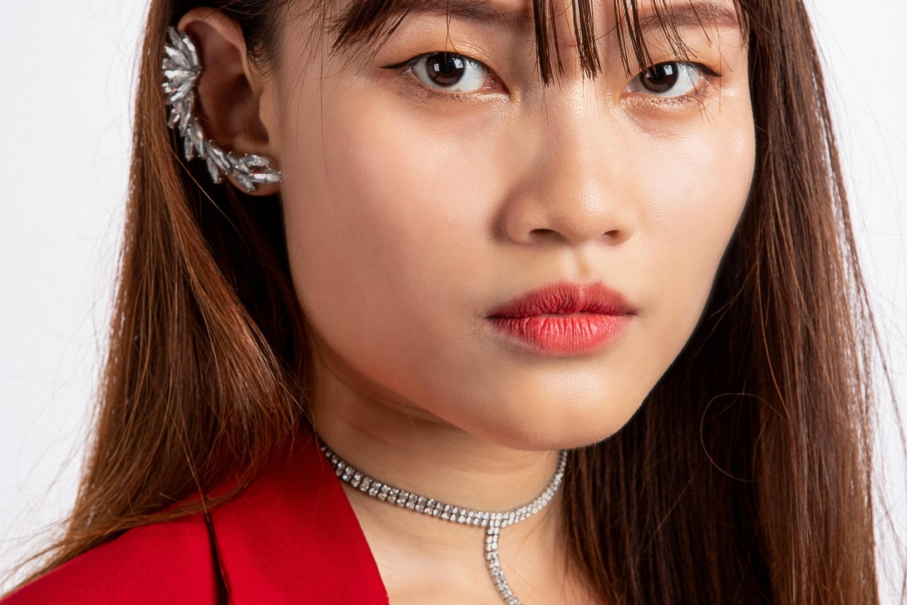 A close-up of an elegant woman wearing a bold diamond choker and ear cuff. A close-up of an elegant woman wearing a bold diamond choker and ear cuff.