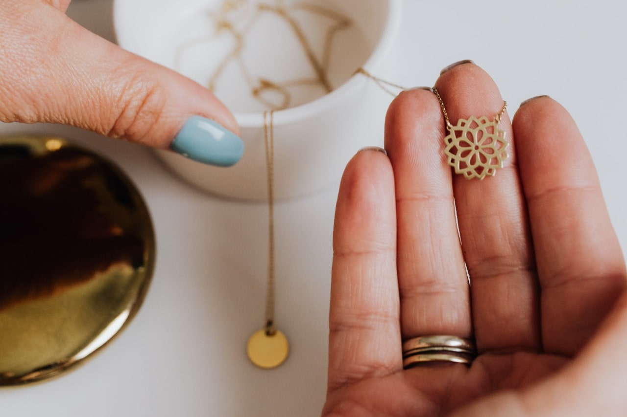 A woman holding a gold pendant necklace. A woman holding a gold pendant necklace.