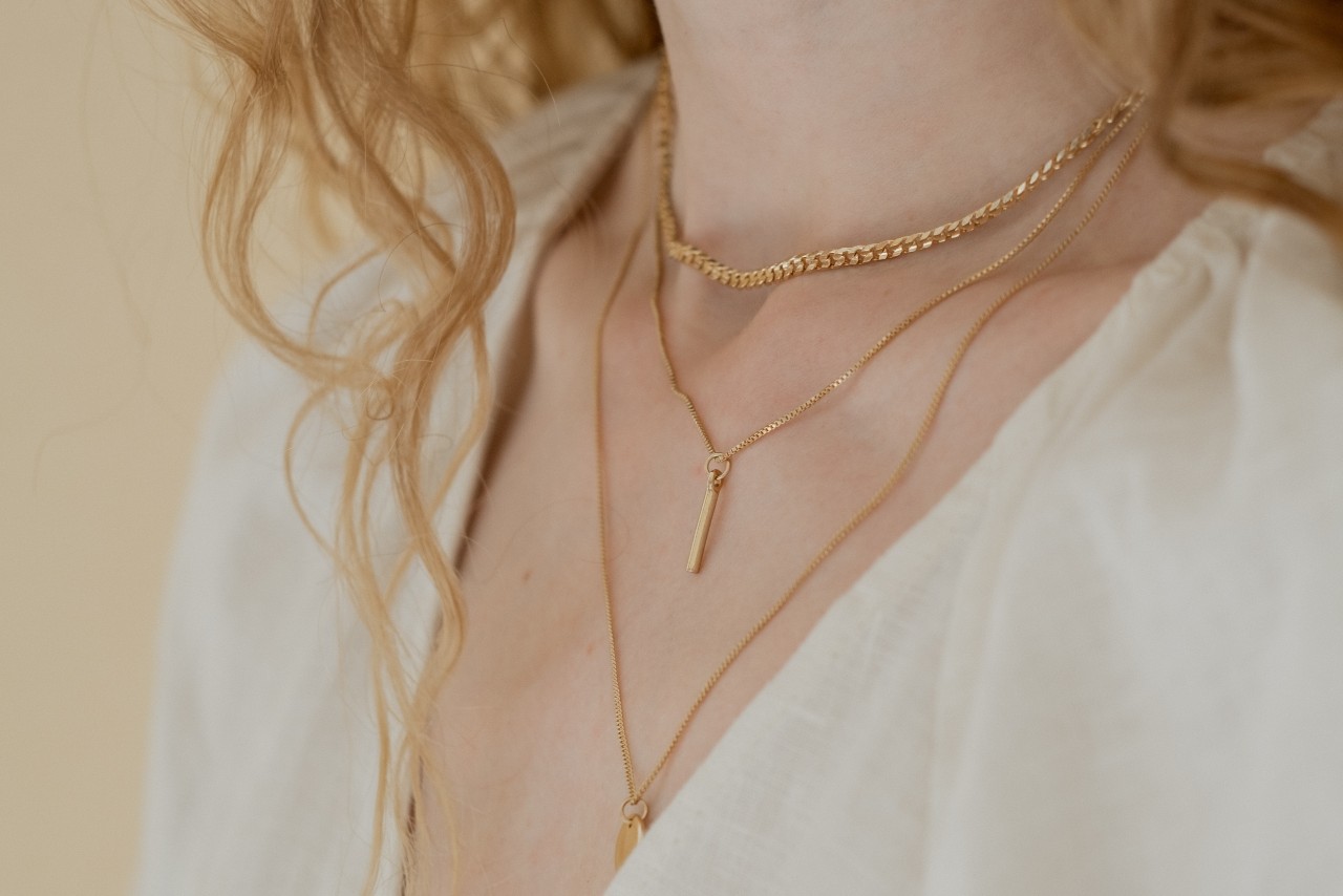 A closeup of a woman’s neck sporting three yellow gold necklaces. A closeup of a woman’s neck sporting three yellow gold necklaces.