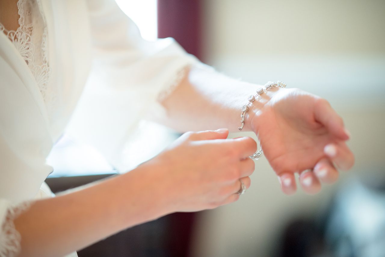 A close-up of a woman putting a diamond bracelet on her wrist. A close-up of a woman putting a diamond bracelet on her wrist.