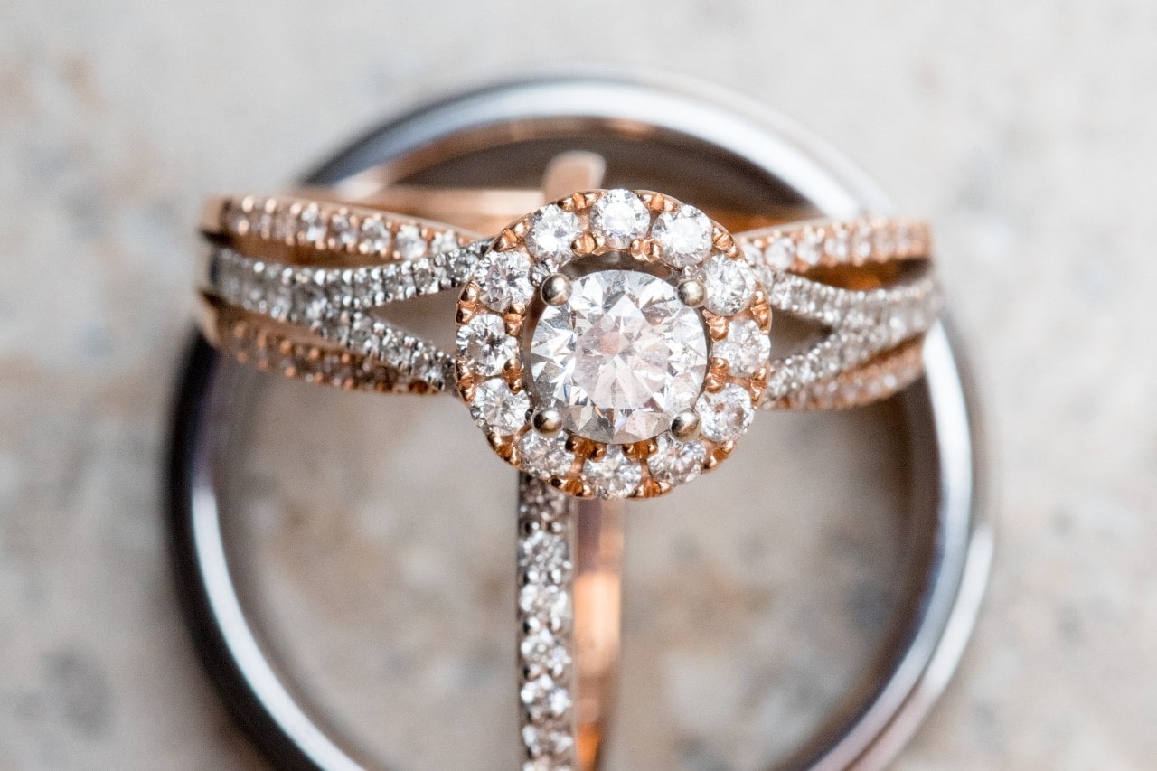 A rose gold split shank engagement ring with a diamond halo set on a silver wedding band. A rose gold split shank engagement ring with a diamond halo set on a silver wedding band.