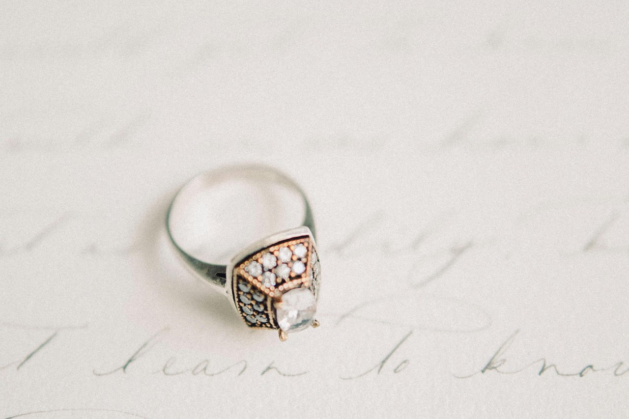A unique and ornate engagement ring displayed atop hand-written wedding vows. A unique and ornate engagement ring displayed atop hand-written wedding vows.